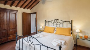 Un dormitorio con cama, armario de madera y mesita de noche con lámpara y vaso de zumo de naranja.