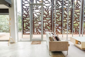 Un interior modern amb un sofà, una taula de centre i una paret decorativa amb dibuixos abstractes.