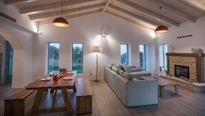 A spacious living area with a wooden dining table, a sofa, and a fireplace. - Exclusive Sea View Villa Madelaine (SPARTIA)