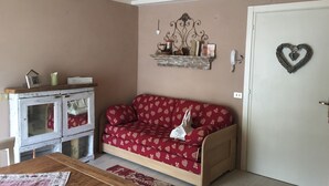A cozy room with a red patterned sofa, a small wooden table, and a vintage cabinet. - House in the center of Ponte di Legno (Ponte di Legno)