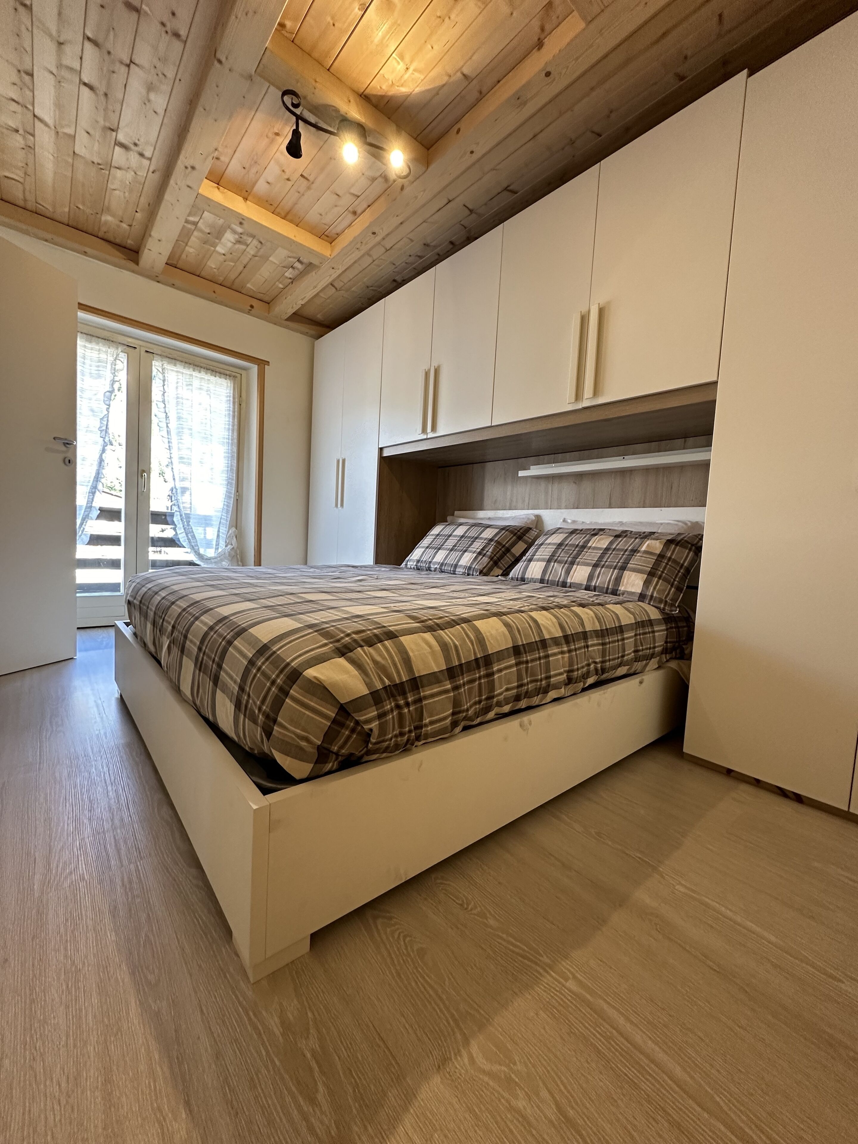 Una camera da letto con un letto, soffitto in legno e armadi a muro.