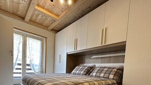 A bedroom with a bed, wooden ceiling, and built-in cabinets. - House in the center of Ponte di Legno (Ponte di Legno)
