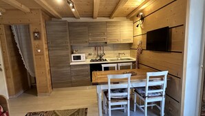 A wooden interior with a kitchen, dining area, and a patterned rug. - House in the center of Ponte di Legno (Ponte di Legno)