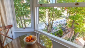 Blick aus einem Fenster, auf dem Tisch eine Schale mit Obst. Fluss mit Booten und Bäumen im Hintergrund sichtbar.