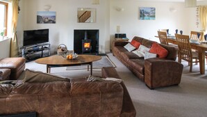 Ein Wohnzimmer mit Kamin, Ledersofas, einem Couchtisch und einem Essbereich mit Stühlen und Tisch.
