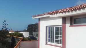 Un edificio con balcón de tejas, una ventana y vista al mar.