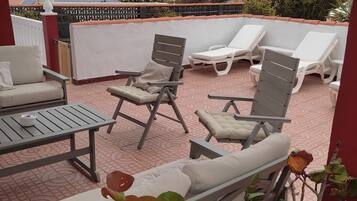 Relax on the rooftop terrace with a clear view of the sea, surrounded by lush plants and comfortable lounge seating.