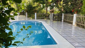 A swimming pool with a tiled deck, surrounded by a wooden fence and potted plants. - Self catering Barranco de la Salud for 11 people (Nevada)