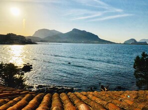 A coastal view with a calm sea, distant mountains, and a tiled roof in the foreground. - Incanto Apartment Golfo Aranci Sardinia, front sea apartment (Golfo Aranci)