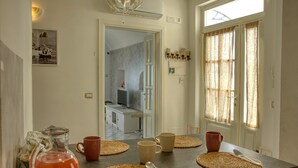 Una cocina con encimera oscura, lámpara colgante y vista hacia la habitación contigua.