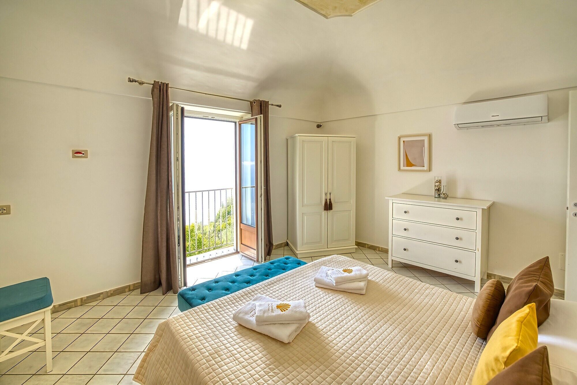 Ein Hotelzimmer mit Bett, Schminktisch, Bank und Balkon.