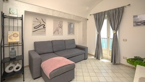 Una sala moderna con un sofá gris, un plaid rosa y arte abstracto en la pared.