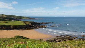 A coastal landscape with a sandy beach, rocky shoreline, and grassy hills. - 2 Bed Caravan, South Devon Coast nr Plymouth, 200m to Beach + Indoor Heated Pool (PLYMOUTH)