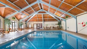 An indoor swimming pool with a wooden ceiling and a view of the surrounding area including a door and a wall with a life preserver. - 2 Bed Caravan, South Devon Coast nr Plymouth, 200m to Beach + Indoor Heated Pool (PLYMOUTH)