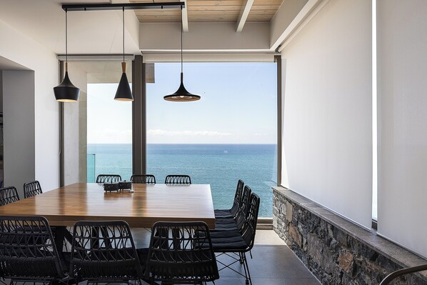 A dining area with a wooden table and black chairs, overlooking a body of water. - Fotinari Villa II -High quality above a cozy beach (Rethymno)