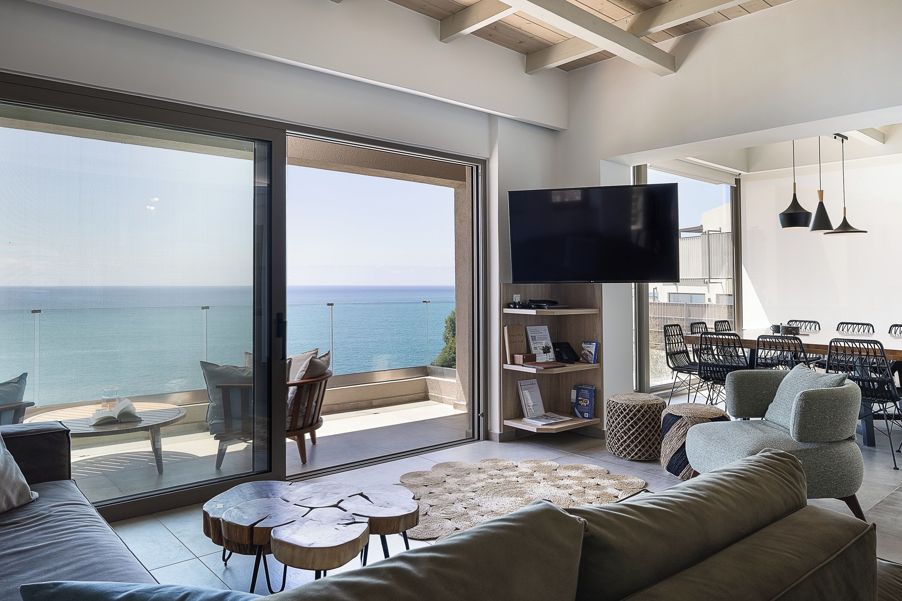 Una sala de estar moderna con un amplio ventanal corredero que da a un balcón con vistas al mar.