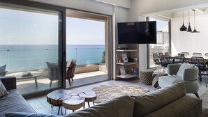 Un salon moderne doté d’une grande porte-fenêtre coulissante donnant sur un balcon avec vue sur la mer.