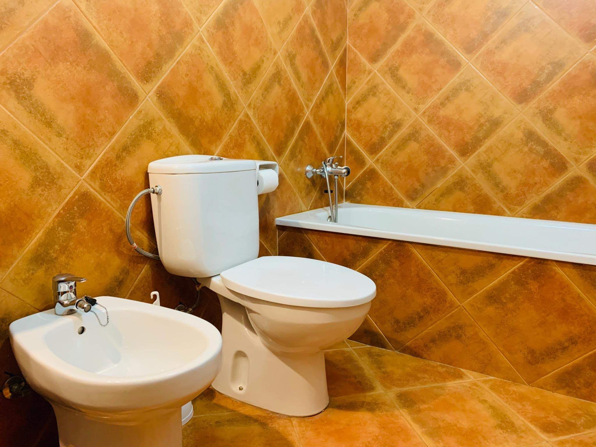 Un baño con inodoro, bidé y lavamanos.