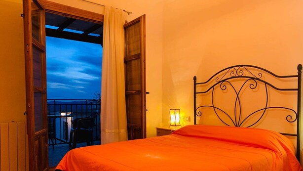 A bedroom with a bed, a nightstand, a window with curtains, and a view of the sky. - Self catering Barranco de la Salud for 2 people (Nevada)