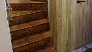Un escalier en bois avec une rampe en corde menant à une porte en bois.