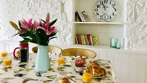Une table de petit-déjeuner avec des croissants, du jus d’orange et un vase de fleurs.
