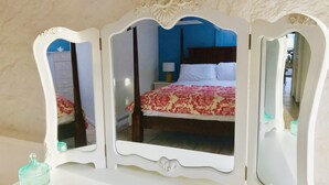 Une chambre à coucher comprenant un lit, une commode et un miroir avec un cadre décoratif.