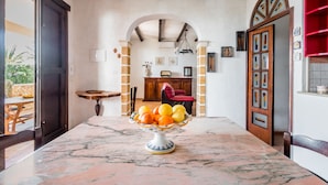 A marble table with a fruit bowl, a wooden chair, and a red armchair in a room with exposed beams and a fireplace. - ARIANNA 'S HOUSE WITH VIEW SEA AND WI. FI (Avola)