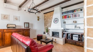 A cozy living room with a leather sofa, a fireplace, a bookshelf, and a wooden cabinet. - ARIANNA 'S HOUSE WITH VIEW SEA AND WI. FI (Avola)