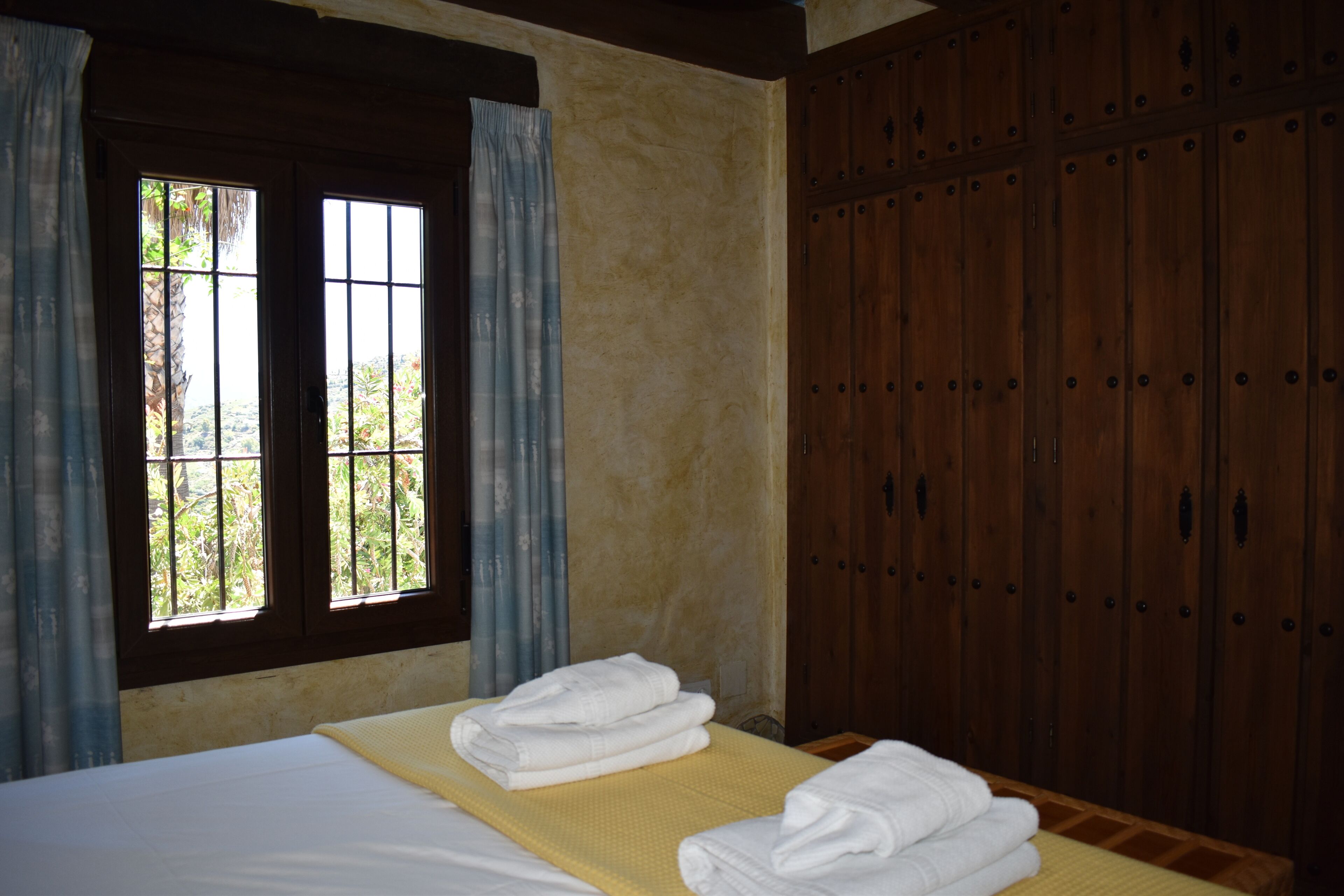 Ein Zimmer mit einem Bett, einem Vorhangfenster und Holzschränken.