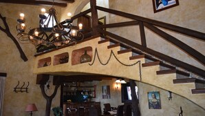 A rustic interior with exposed wooden beams, a chandelier, and a staircase leading to an upper level. - Finca Ortiz with private pool for 6 people and fantastic views (Cómpeta)