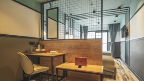 A modern room with a wooden floor, a desk with a chair, a small table, a sofa, and a large mirror. - City Life Demir Hotel (Fethiye)