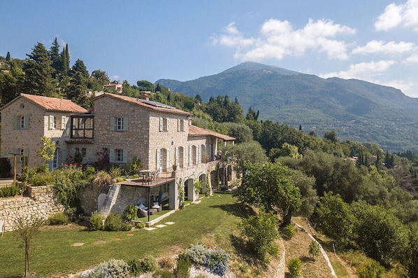 A stone villa with a garden and a mountain backdrop. - Charm, luxury, stunning views, spacious villa with heated pool, aircon and games (Le Bar-sur-Loup)