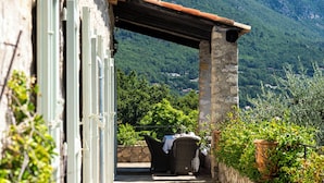 Une terrasse extérieure aménagée avec des meubles en osier et une table, offrant une vue sur un paysage montagneux.