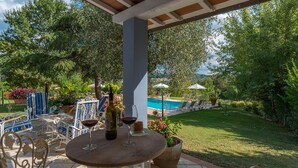 A covered outdoor seating area with a pool in the background. - Villa Leonardo 30+6, Emma Villas (Figline e Incisa Valdarno)
