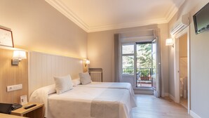 Habitación de hotel con dos camas, un escritorio con teléfono, un radiador y vistas al exterior.