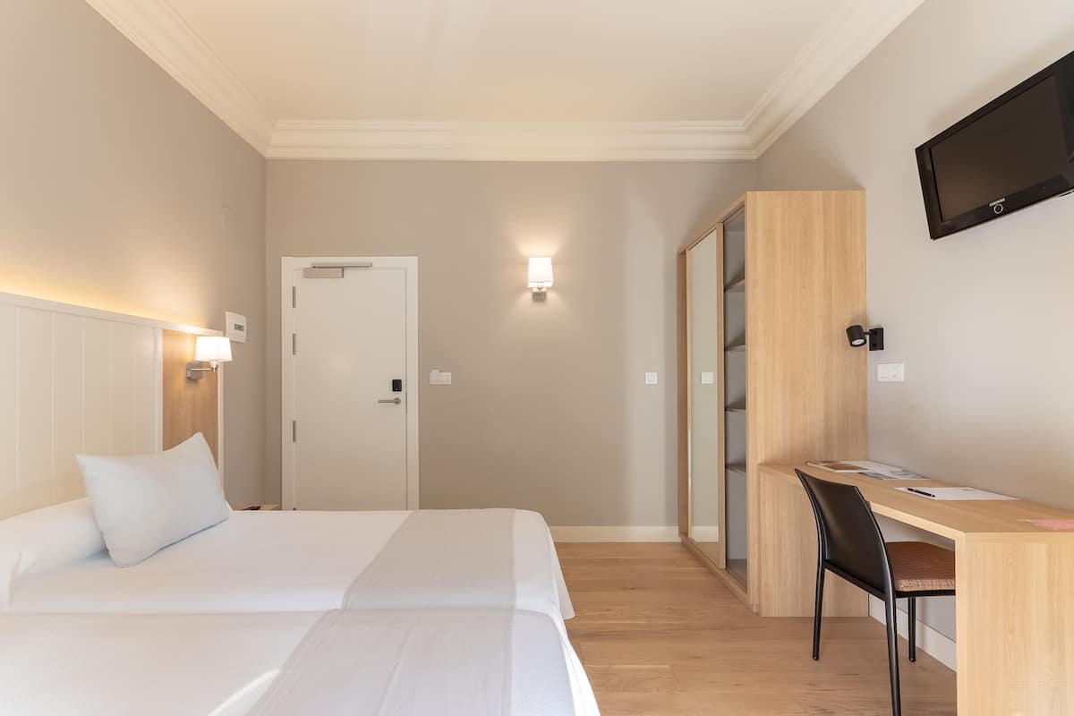 Een hotelkamer met een bed, een bureau en een televisie.