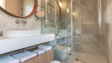A modern bathroom with a glass-enclosed shower, a white sink, and a wooden vanity.