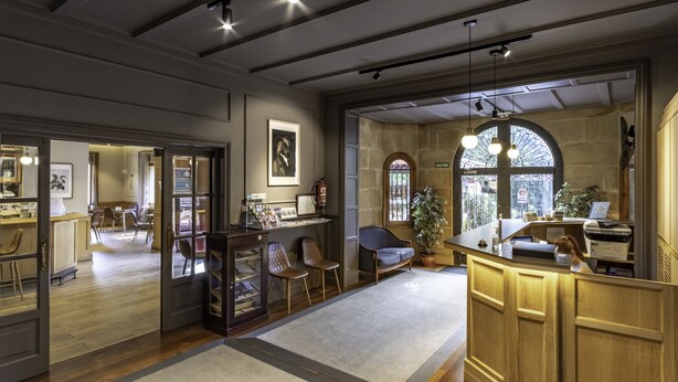 Un lobby amplio con un mostrador de recepción de madera, zona de estar y vistas al exterior a través de grandes ventanales.