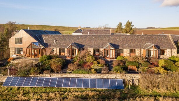 A row of stone houses with solar panels in front.