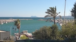 Un port de plaisance avec des bateaux, un phare et un palmier.
