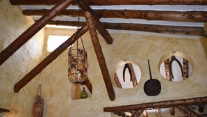 A rustic interior with wooden beams, a hanging lantern, and circular windows with hanging items. - Finca Durillo with private pool for 6 people (Competa)