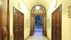 A hallway with wooden doors and a tiled floor leading to an outdoor area. - Villa Franchetti - Luxurious Florentine Villa with Swimming Pool (Firenze)