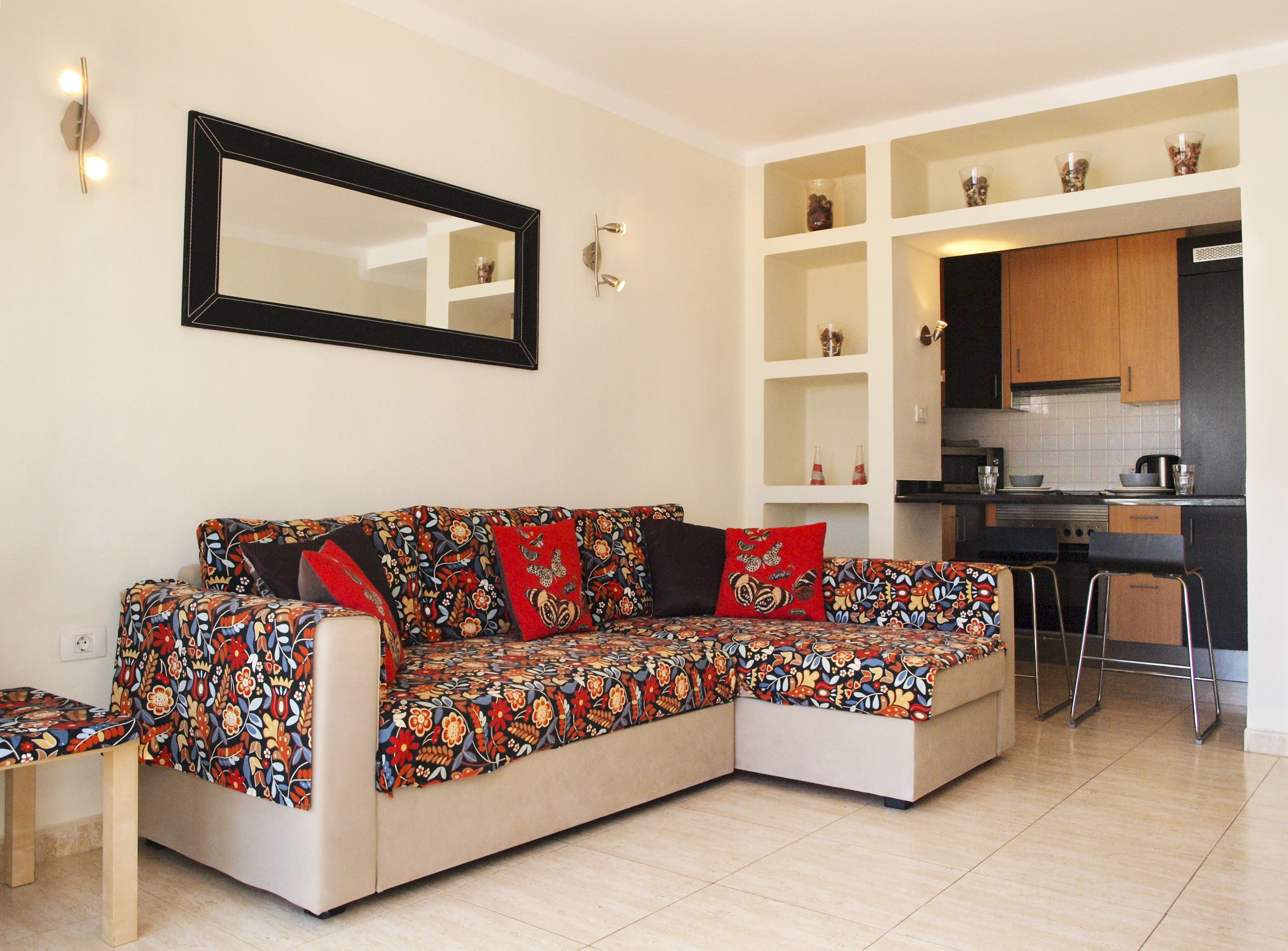 Una sala de estar con un sofá, una mesa de centro y una zona de cocina con armarios y encimera.