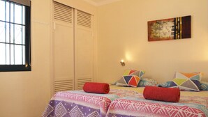 Une chambre à coucher comprenant un lit, une fenêtre, une œuvre d’art accrochée au mur et un luminaire.