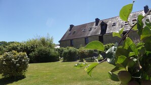 A stone building with a sloped roof, surrounded by a well-maintained lawn and gravel path. - 7 Cottages in 100 acres, heated pool. Near Pont Aven, Concarneau, beaches 15km (Bretagne)