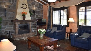 A cozy living room with a stone fireplace, blue leather sofas, a wooden coffee table, and a television. - Finca Higueron with private pool for 6 people and fantastic views (Competa)