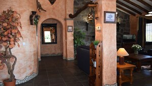 A rustic interior with stone walls, a wooden bench, a table with a lamp, and a potted plant. - Finca Higueron with private pool for 6 people and fantastic views (Competa)