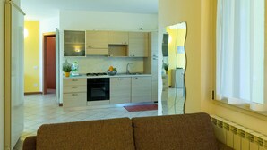 A modern kitchen with light wood cabinets, a built-in oven, and a sink.