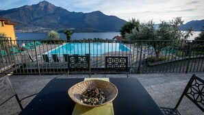 A terrace with a view of a mountain and lake, a pool area, and outdoor seating.