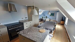 A modern kitchen with granite countertops, a built-in oven, and a dining area with a table and chairs. - Stunning coastal annex with spectacular sea views (Perranuthnoe)